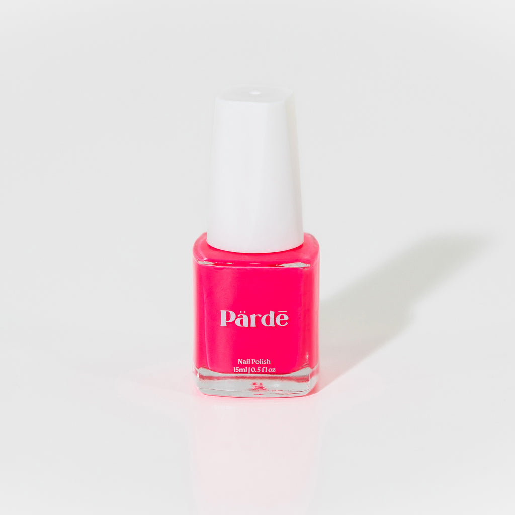 A clear square bottle of hot pink nail polish with a white cap against a white background. 